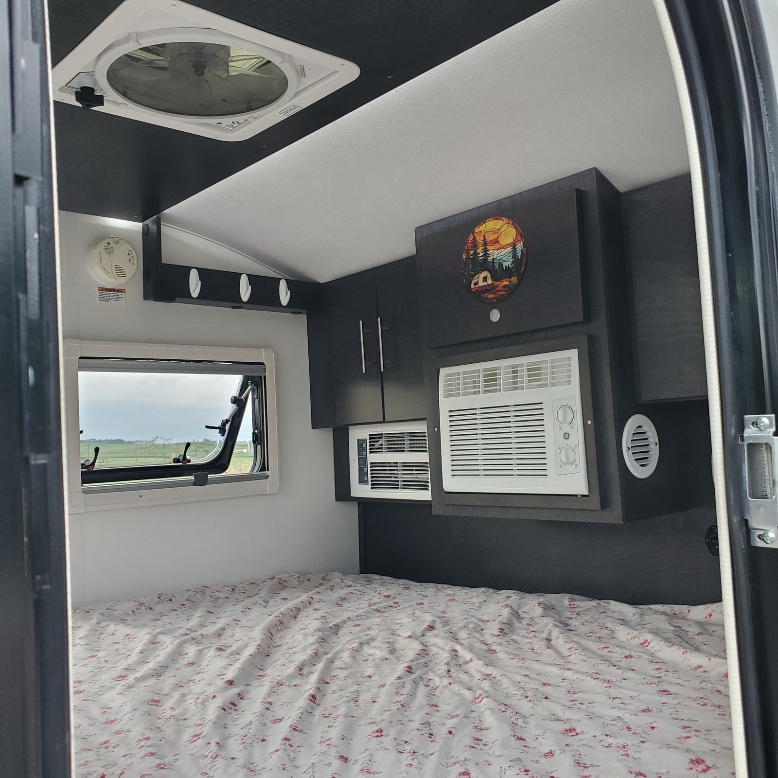 RV rental: Comfortable interior with bed, window, dual AC units, and overhead storage.