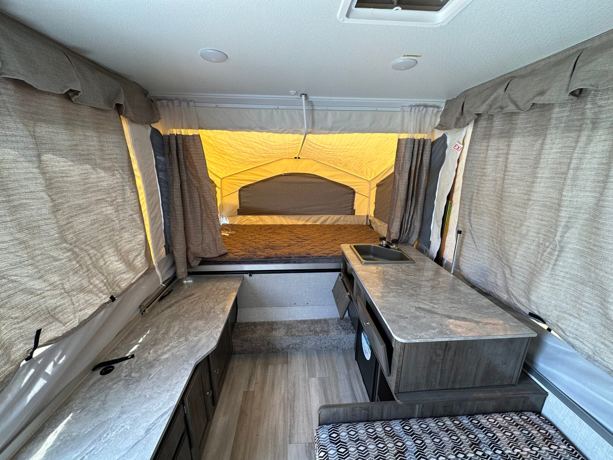 Pop-up camper RV rental interior: kitchen, beds, and living area. Comfortable and compact for your trips. — photo 9