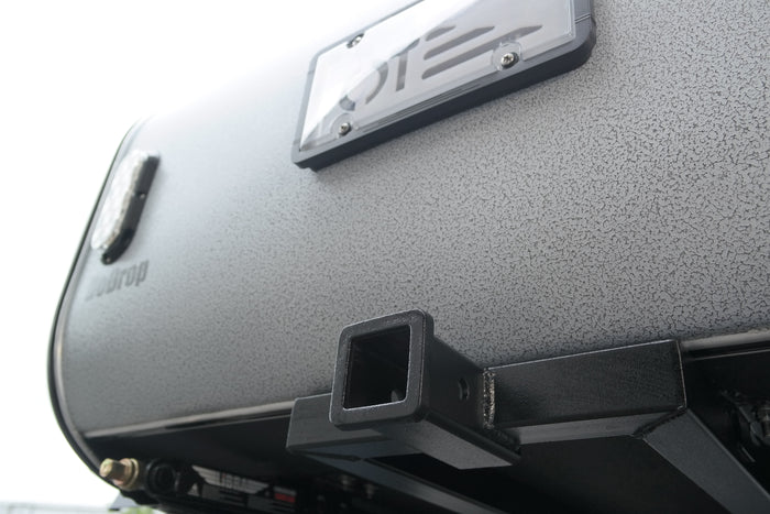 Textured grey Teardrop travel trailer rear, with license plate frame and hitch receiver for RV rental adventures.