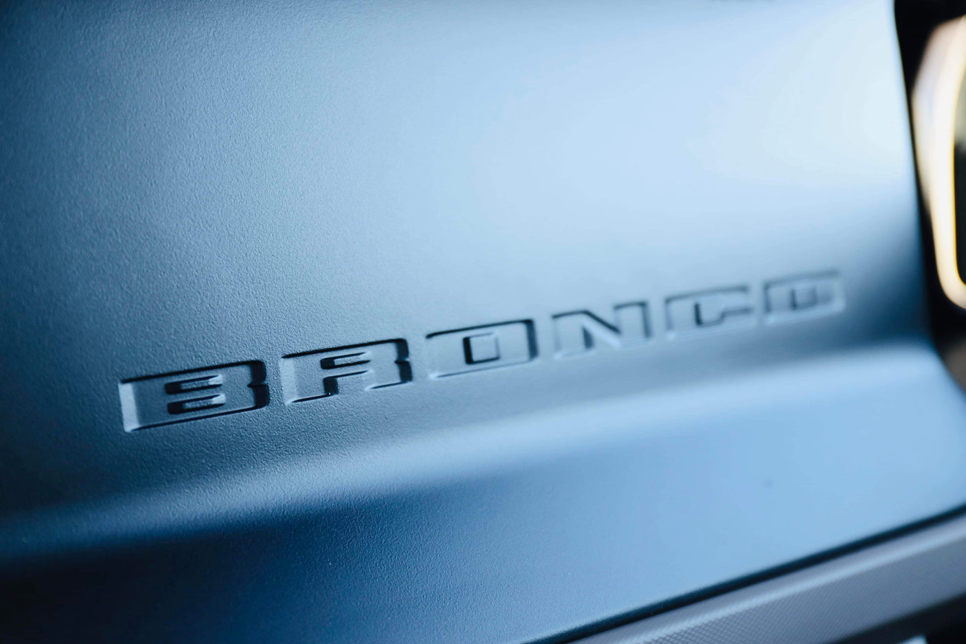 Embossed 'BRONCO' detail on a matte blue vehicle surface, perfect for your next RV rental trip.