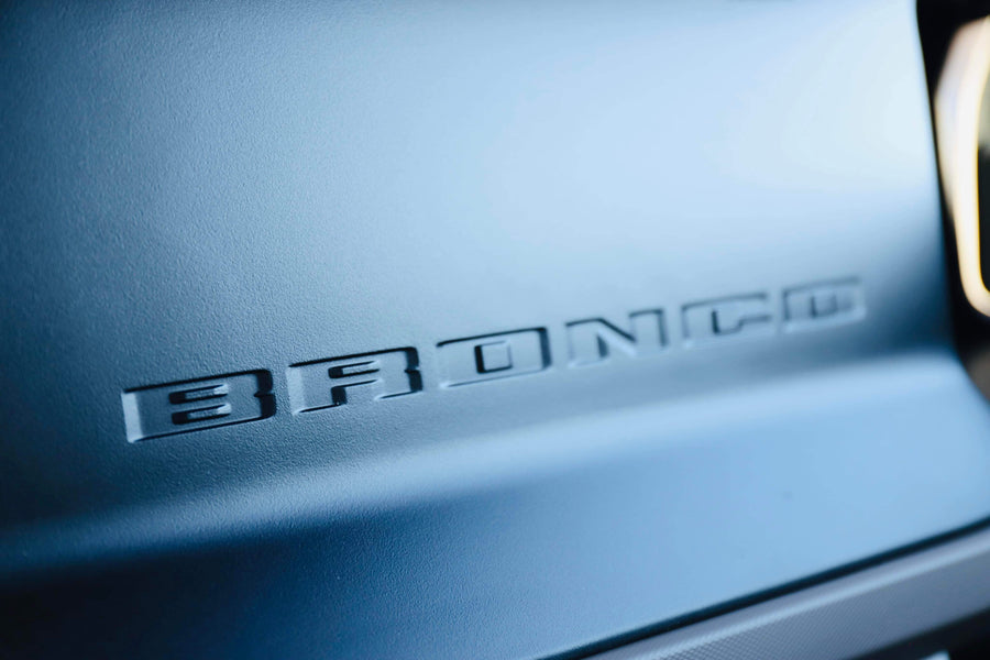 Embossed 'BRONCO' detail on a matte blue vehicle surface, perfect for your next RV rental trip.