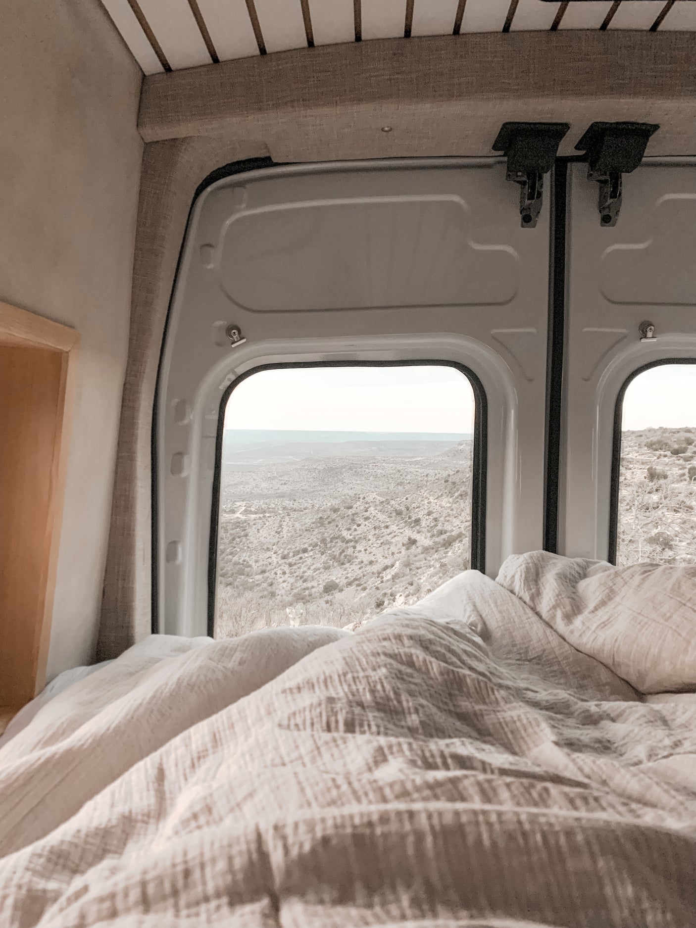 Cozy RV rental bedroom with a stunning desert landscape view from the back windows, perfect for scenic travel.