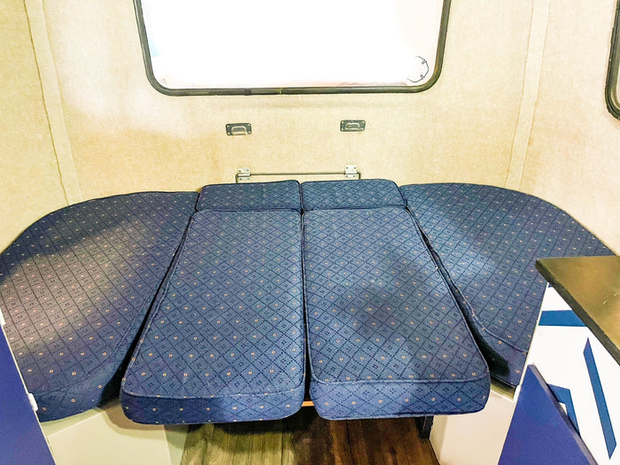 and a large window. Ideal for travel.|Inside a renovated RV rental: a modern blue & white kitchenette