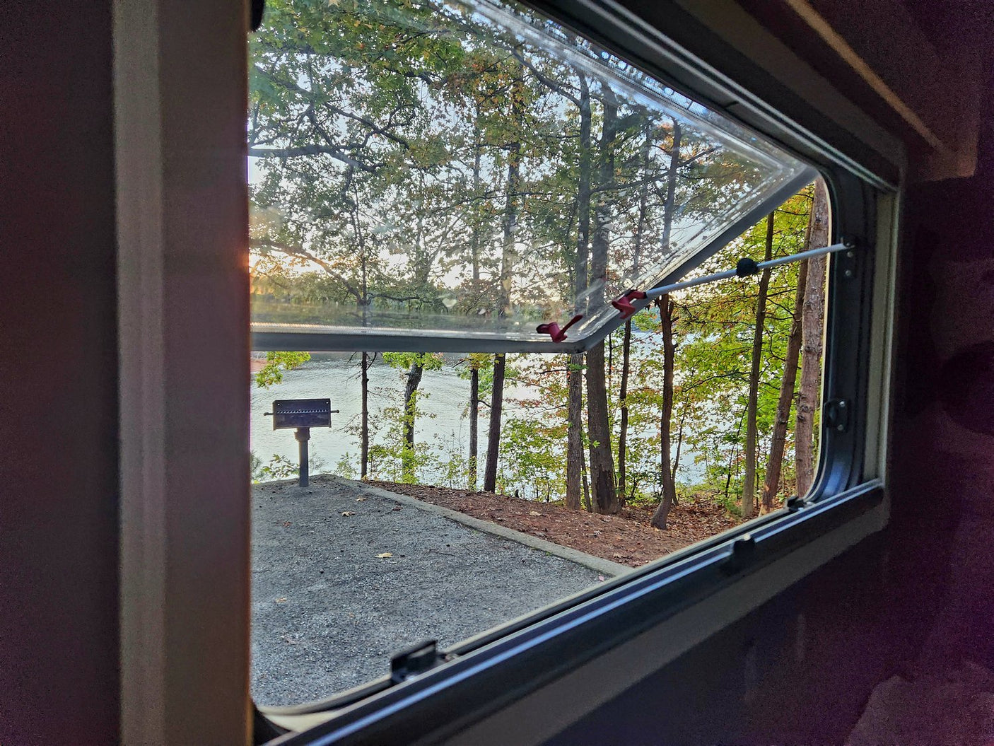 silver teardrop RV rental sits in a sun-dappled forest campsite