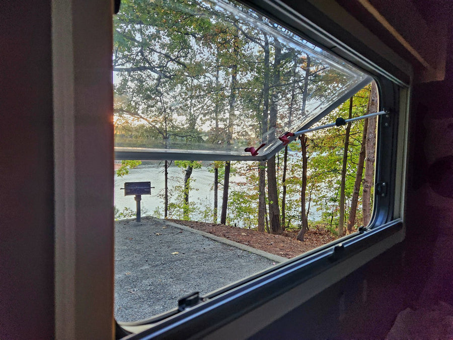 silver teardrop RV rental sits in a sun-dappled forest campsite