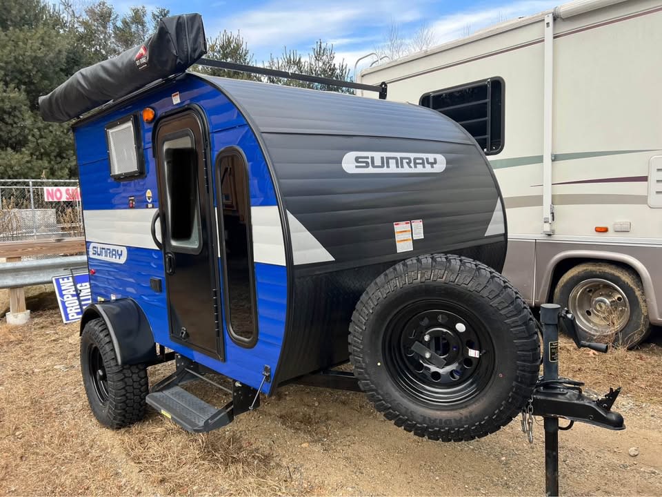 parked against stunning red rock formations.|Blue Sunray teardrop RV rental with off-road tires