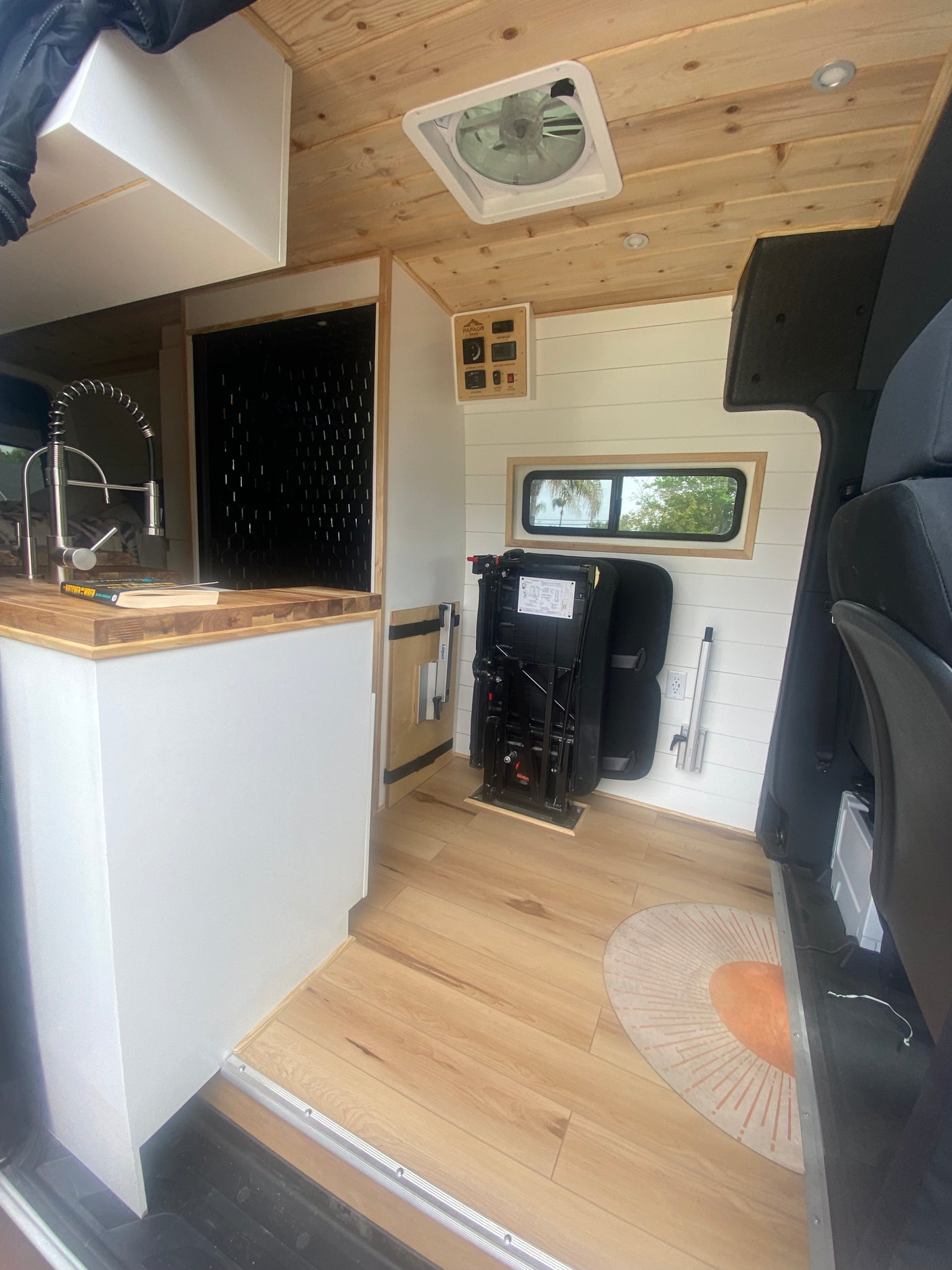 This inviting rv rental shows a camper van interior with a practical kitchen, versatile seating, and warm wood finishes.