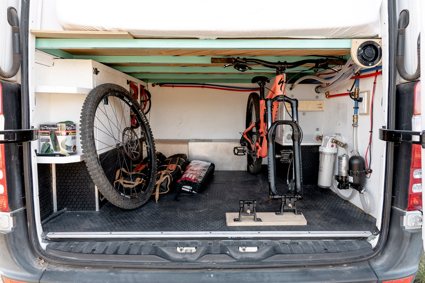 RV rental: efficient storage for a mountain bike (wheel off), water system, and gear in a converted camper van.