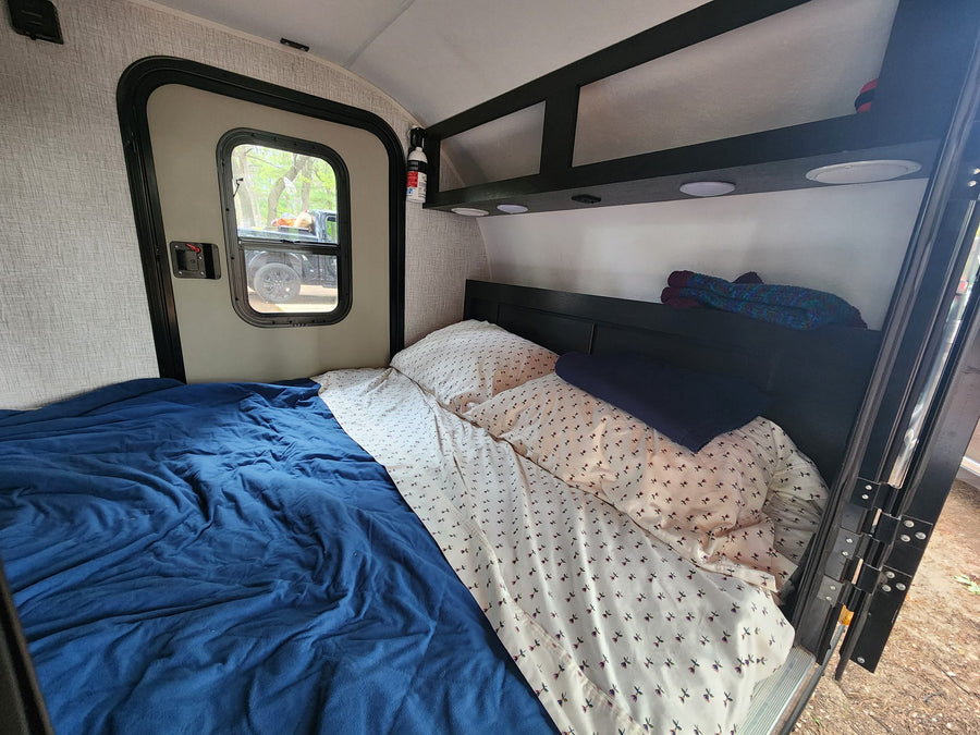 and griddle for comfortable camping.|This RV rental bedroom features a comfy bed with blue sheets