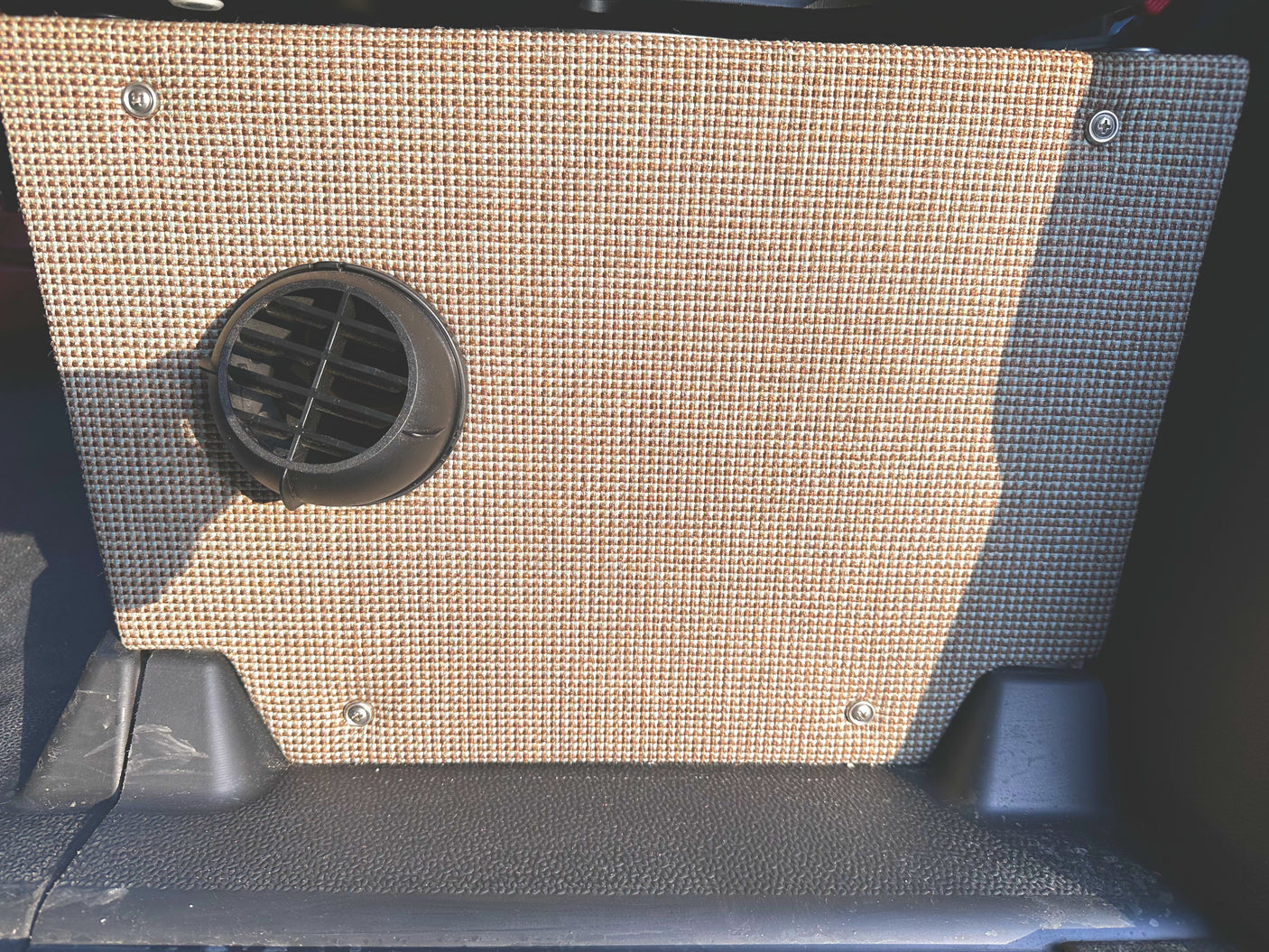 RV rental camper van interior. Beige woven fabric panel with black circular vent & durable floor.