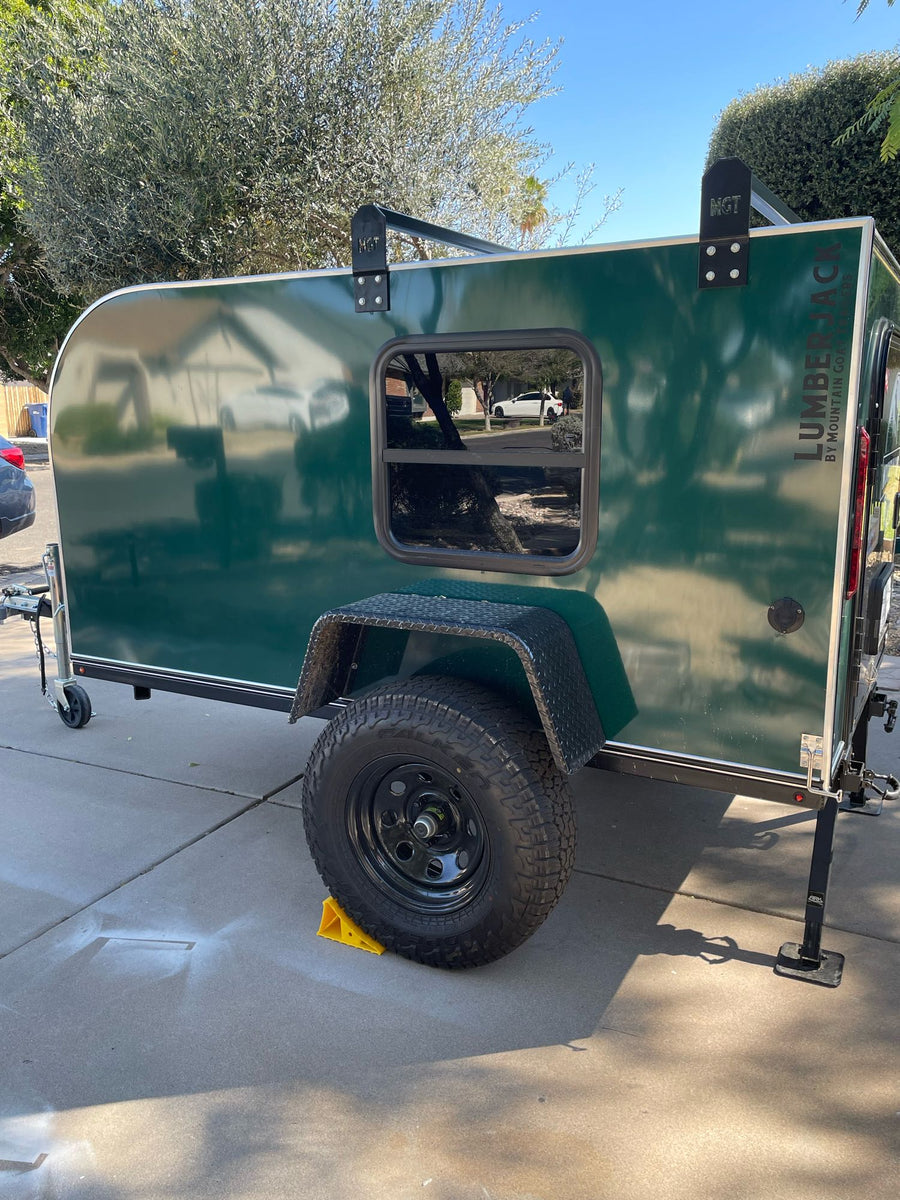 ready for adventure.|Cozy green teardrop RV rental ready for adventure. Open door reveals comfy bed with plaid blanket. Perfect for camping.|This dark green teardrop camping trailer