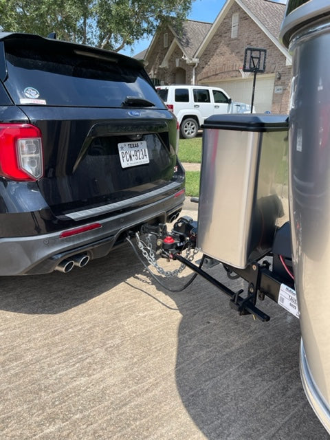 Black SUV towing a silver RV rental, securely connected by hitch & chains for recreational travel. Texas plate visible. — photo 11