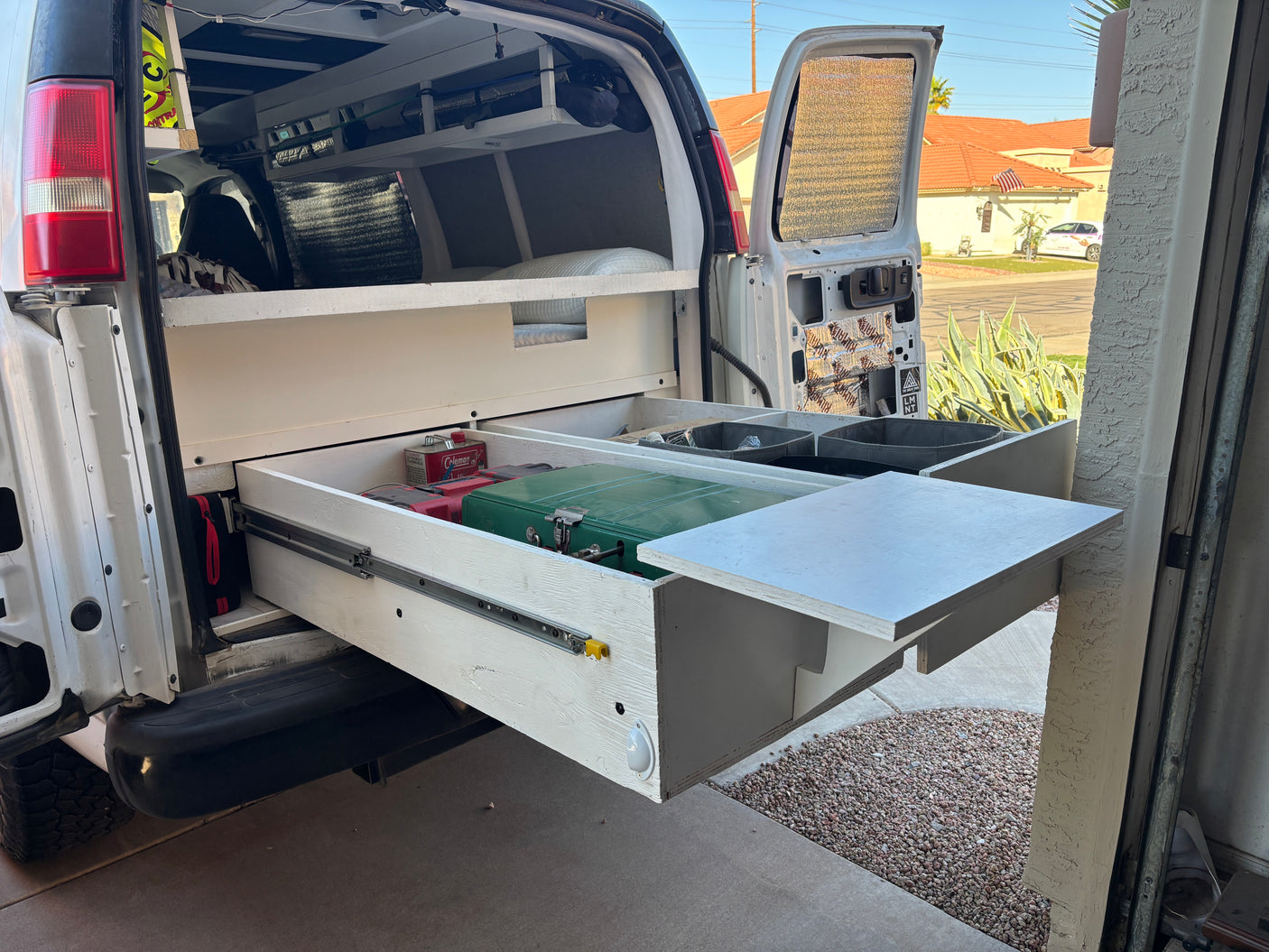 Customized RV rental camper van interior featuring a pull-out kitchen drawer, stove, and organized storage.