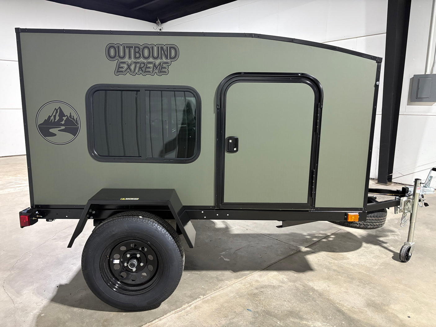 Olive green 'Outbound Extreme' compact camper trailer, ideal for RV rental and outdoor adventures.
