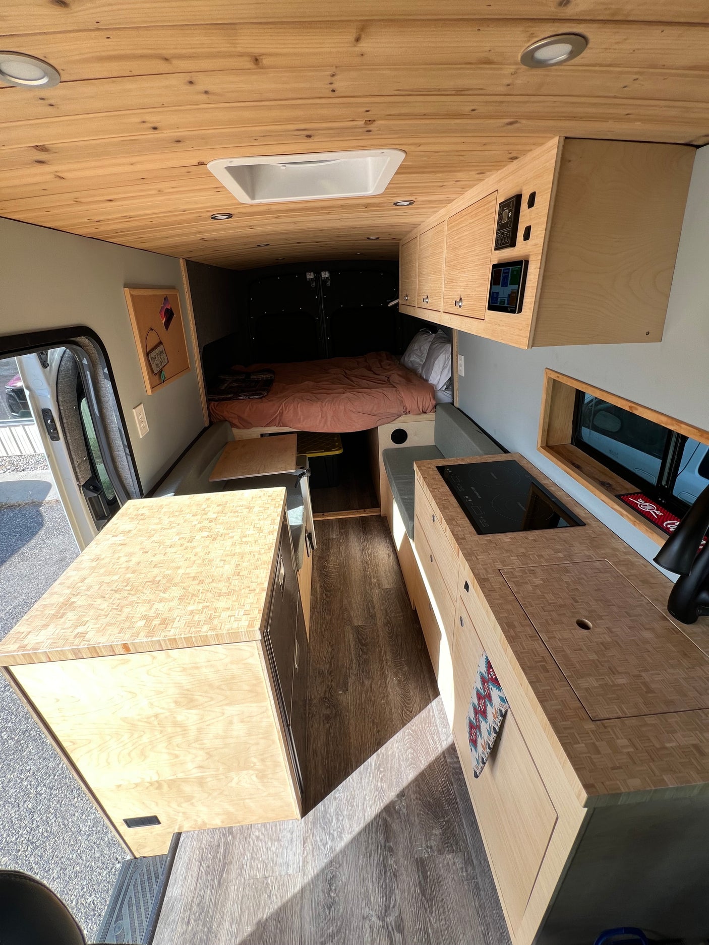 Spacious, modern camper van interior, perfect for your next RV rental adventure. Features wood accents, kitchen, and cozy bed.