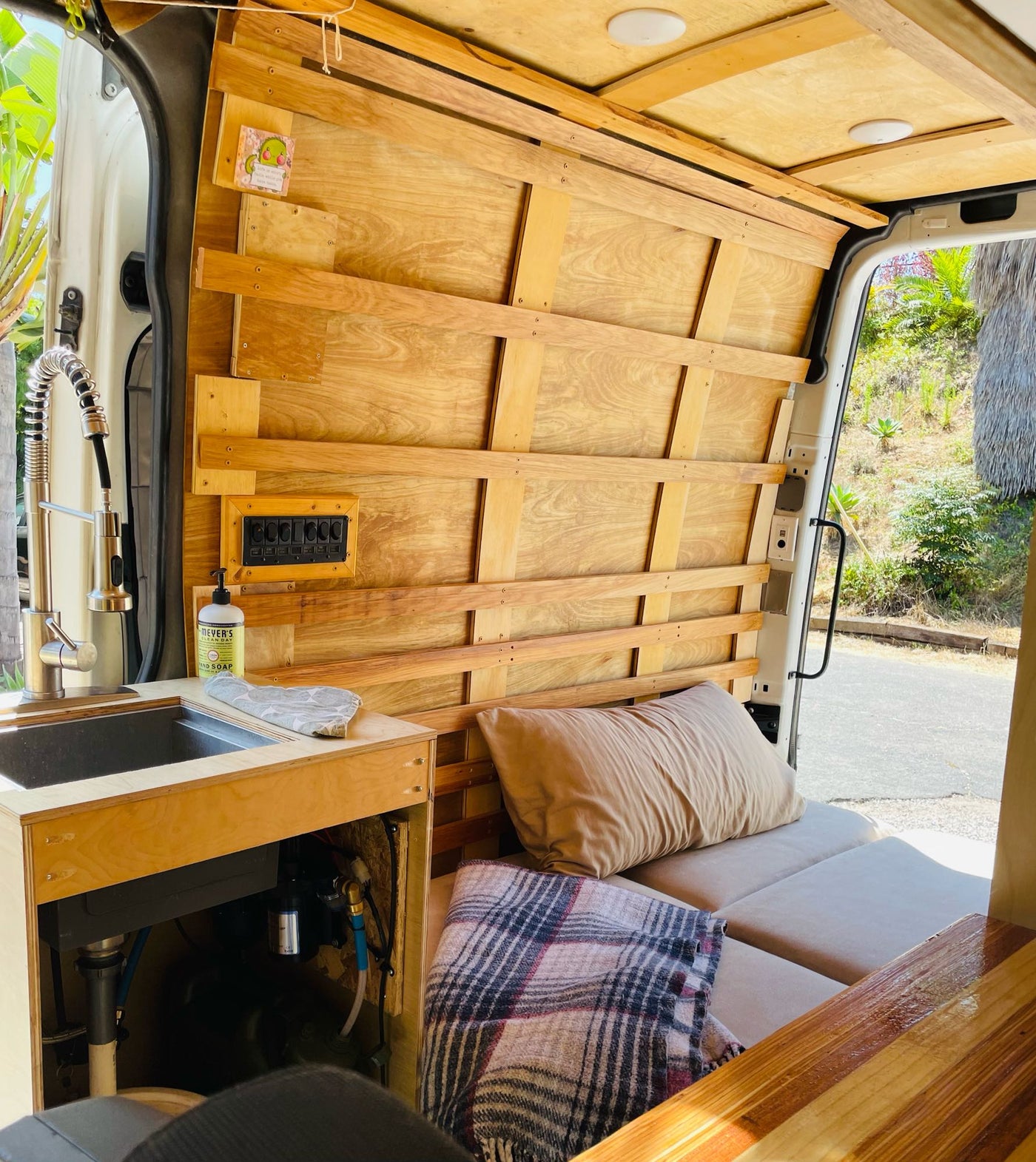 Cozy custom RV rental interior with wooden walls, sink, control panel, and bed area. Perfect for mobile living. — photo 10