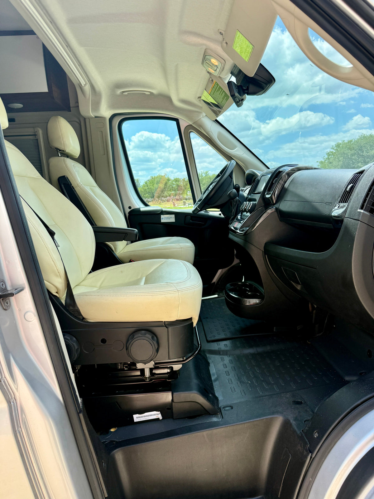 Spacious RV rental front cabin, featuring comfortable cream seats, a functional dashboard, and clear views through the windshield. — photo 3