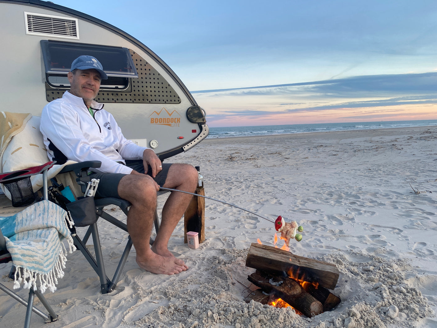 Enjoying beach camping by our RV rental, cooking dinner over a beach bonfire at sunset. A perfect, relaxing getaway!