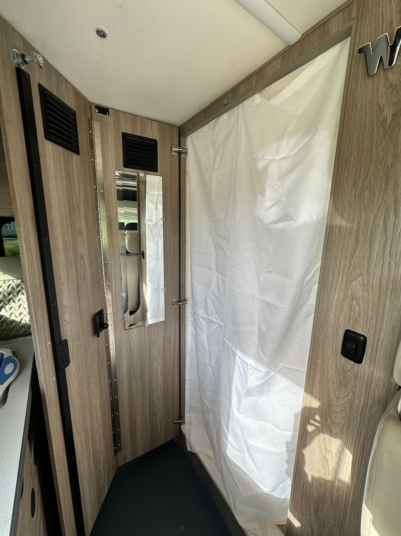 and front seating area visible.|Compact RV rental wet bath featuring a toilet