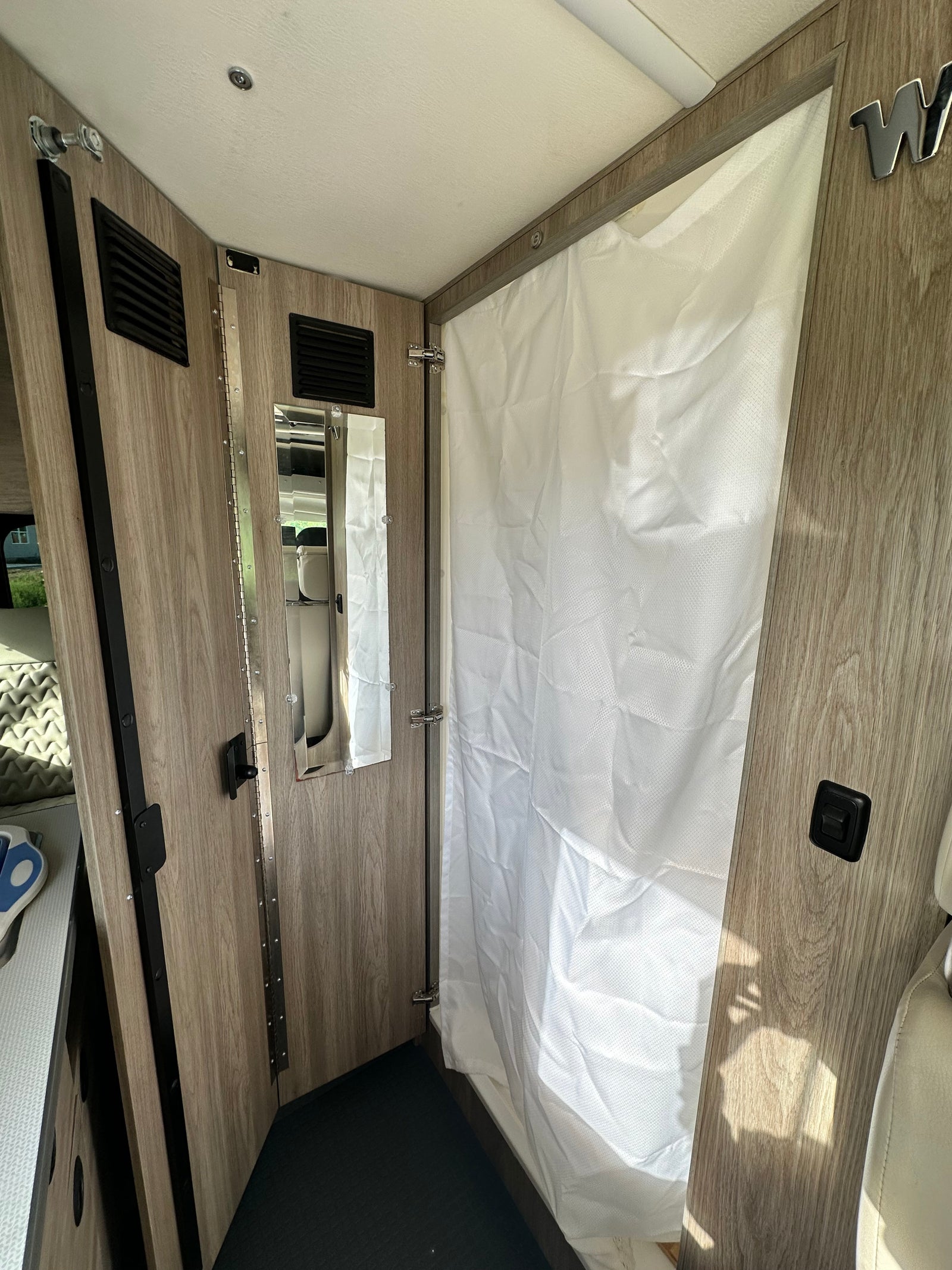 and front seating area visible.|Compact RV rental wet bath featuring a toilet