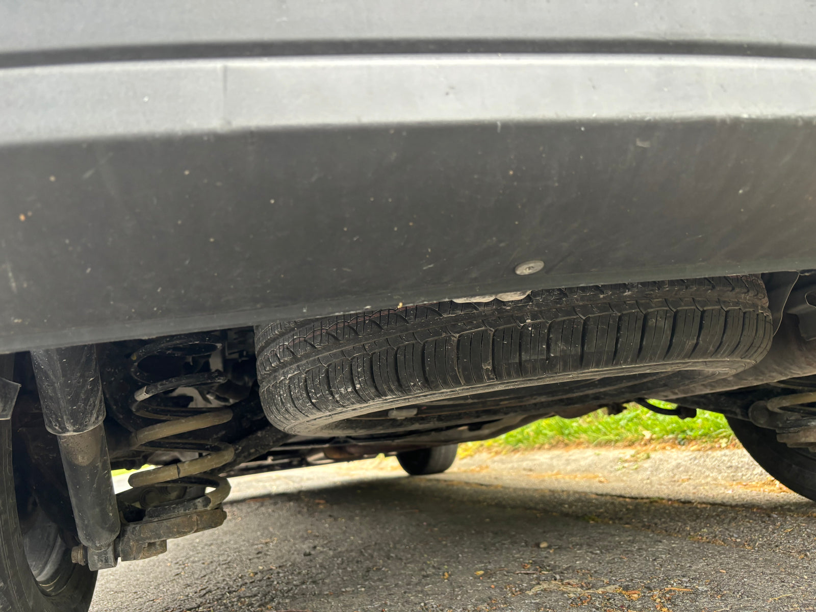 Underside view of an RV rental: spare tire mounted below, with shock absorber and coil spring visible.