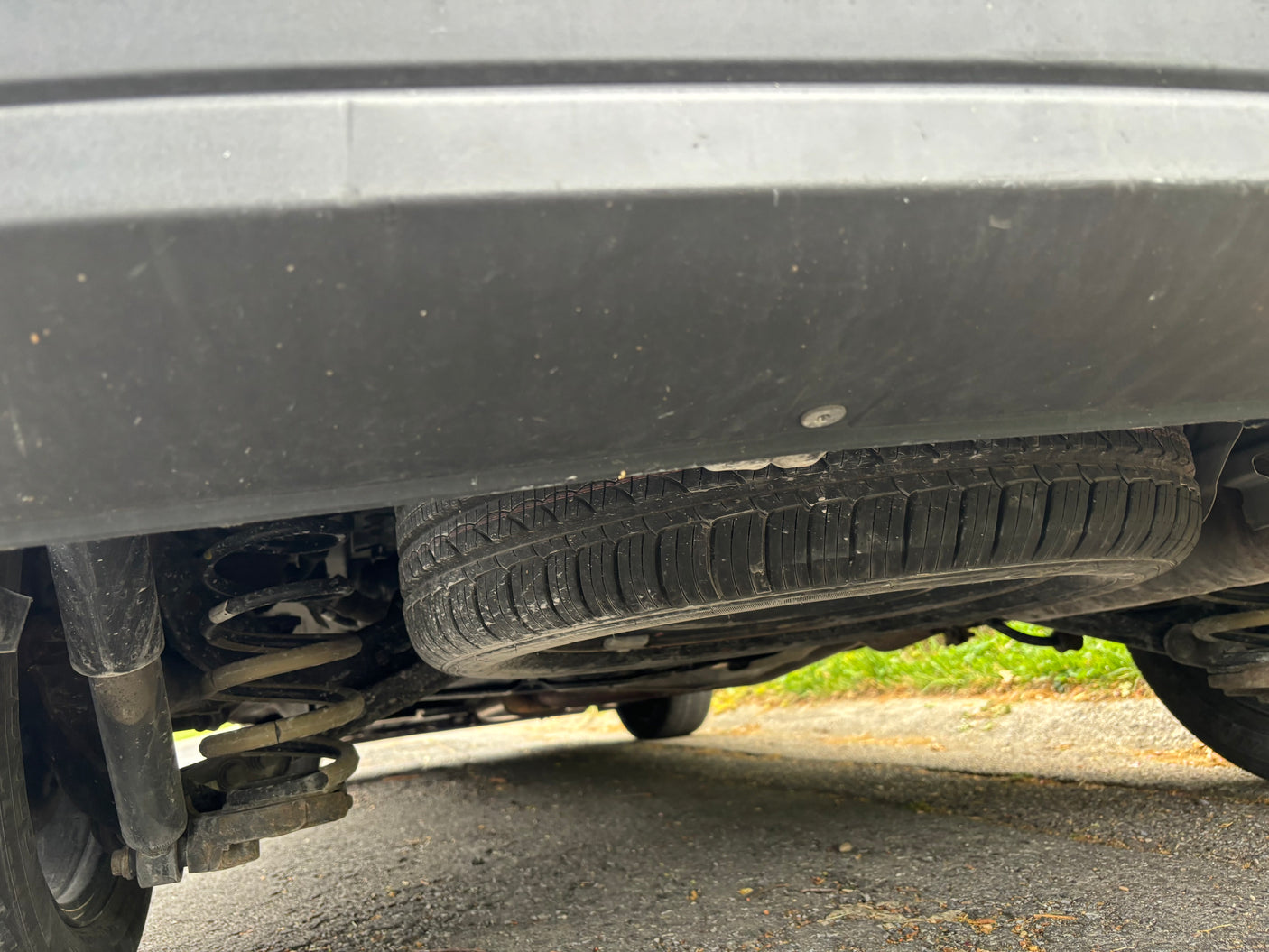 Underside view of an RV rental: spare tire mounted below, with shock absorber and coil spring visible.
