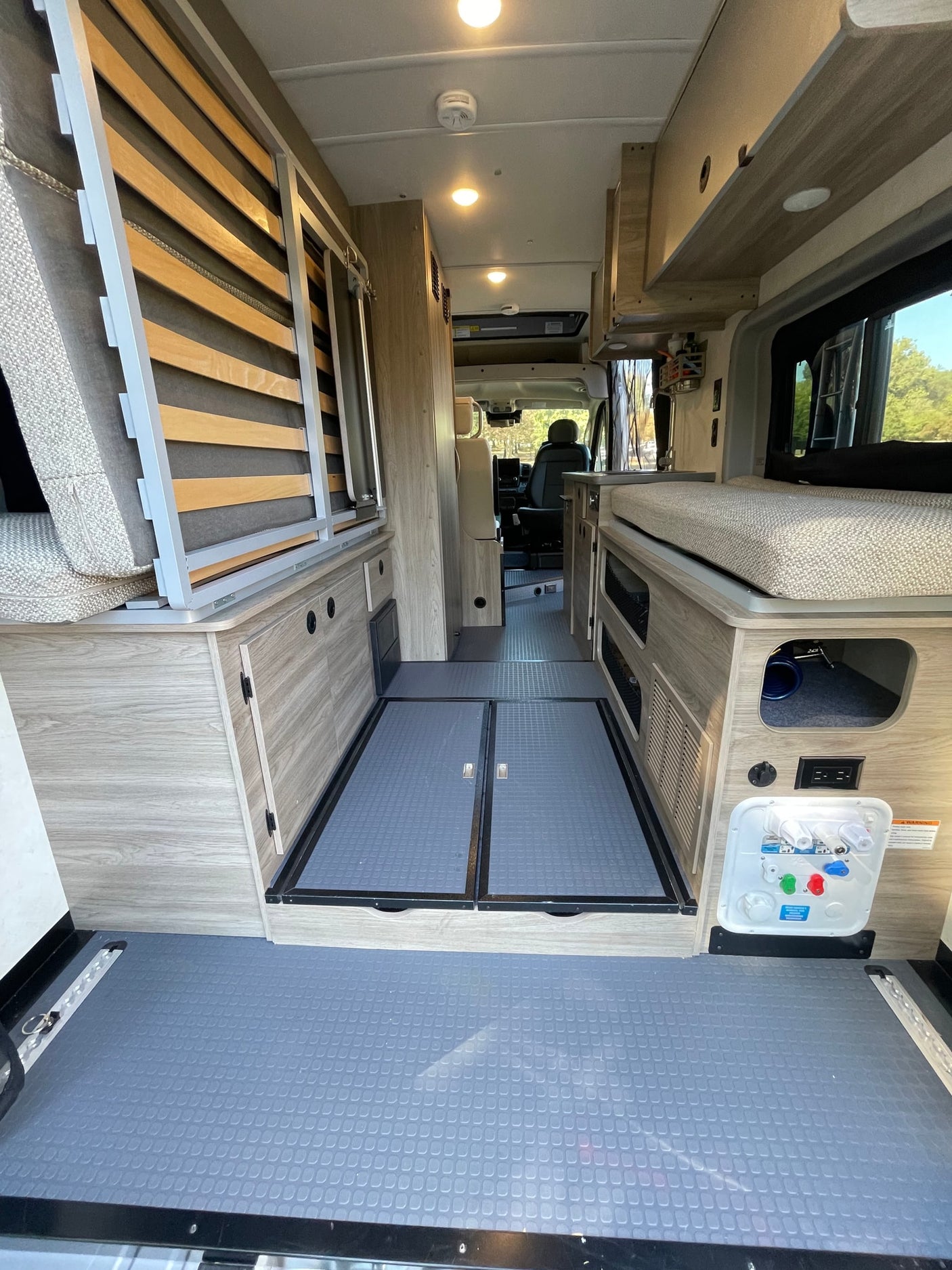 Discover this well-equipped RV rental's interior: convertible bed, storage, utility panel, and easy-clean floors.