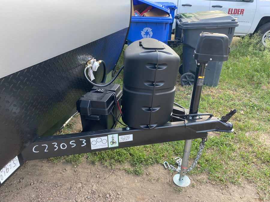 RV rental ready for adventure! Front view of trailer with propane tanks, battery, and hitch. Great for camping trips.