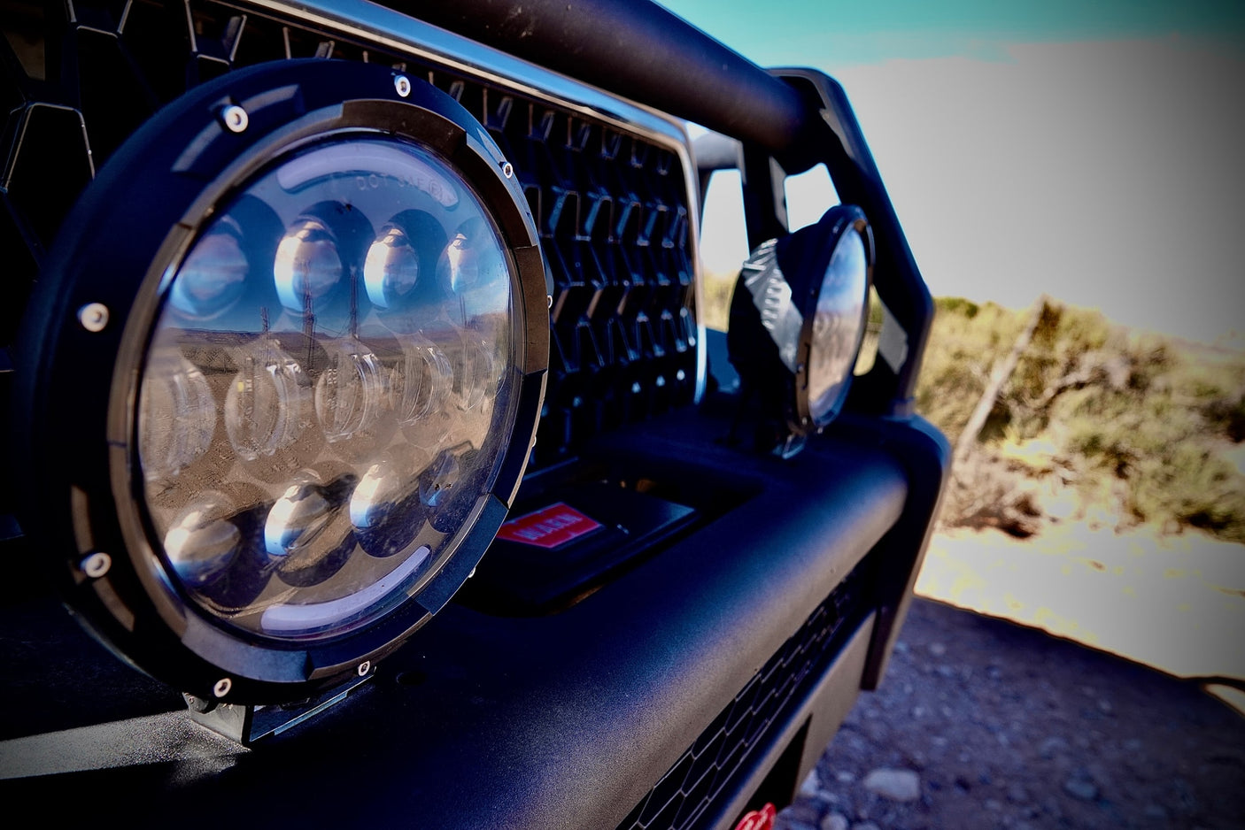 Detail of an RV rental off-road vehicle's LED light, reflecting a desert landscape and utility poles.