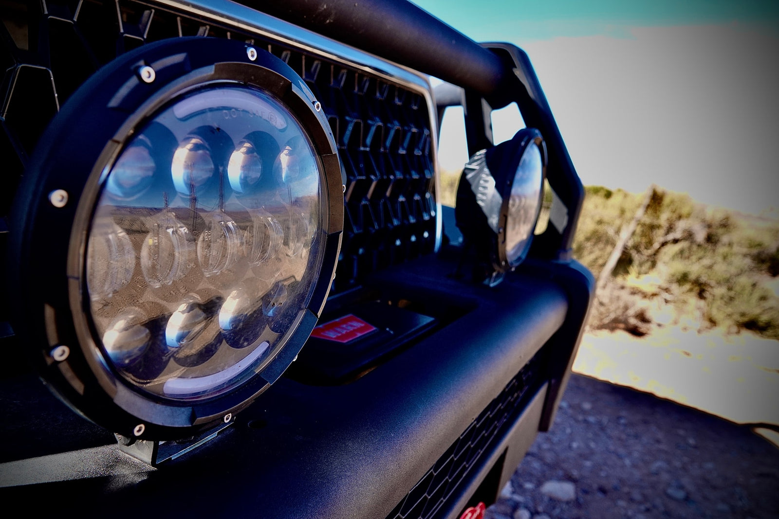 Detail of an RV rental off-road vehicle's LED light, reflecting a desert landscape and utility poles.