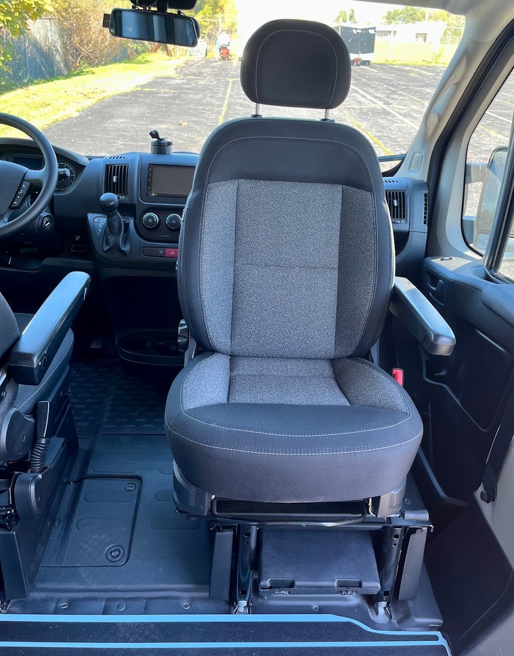 Inside this RV rental: front passenger swivel seat with armrests, dashboard, and road view. Ideal for camper van travel.