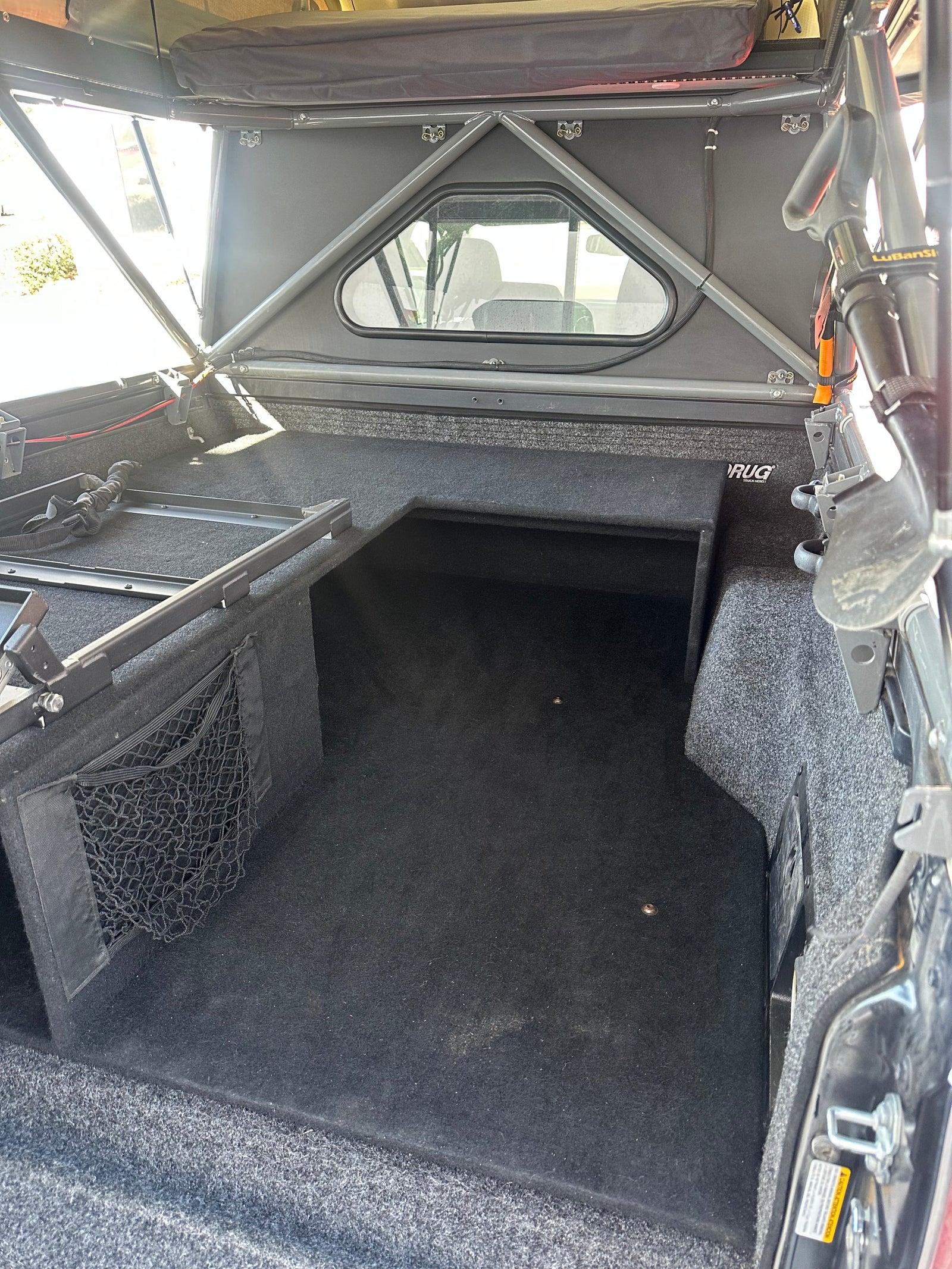 Carpeted truck bed interior with custom storage and topper, ready for your RV rental overlanding adventures.