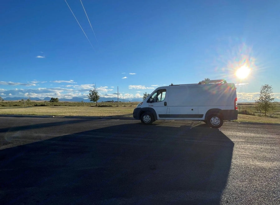 backed by snowy mountains under cloudy skies. Explore the outdoors!|A white cargo van