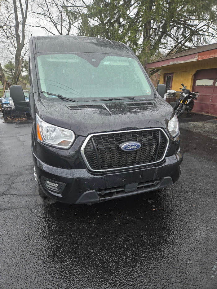 Black Ford Transit van, ideal for RV rental, wet from rain. Parked on a driveway, ready for your next trip.