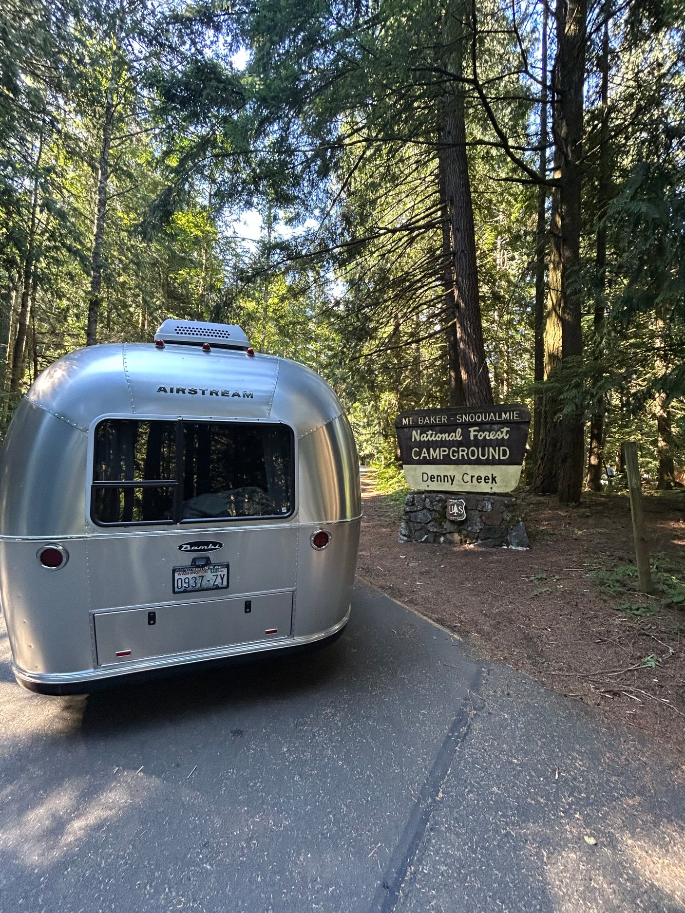 A silver Airstream RV rental parked at the Mt. Baker-Snoqualmie National Forest Campground entrance, Denny Creek, Washington.