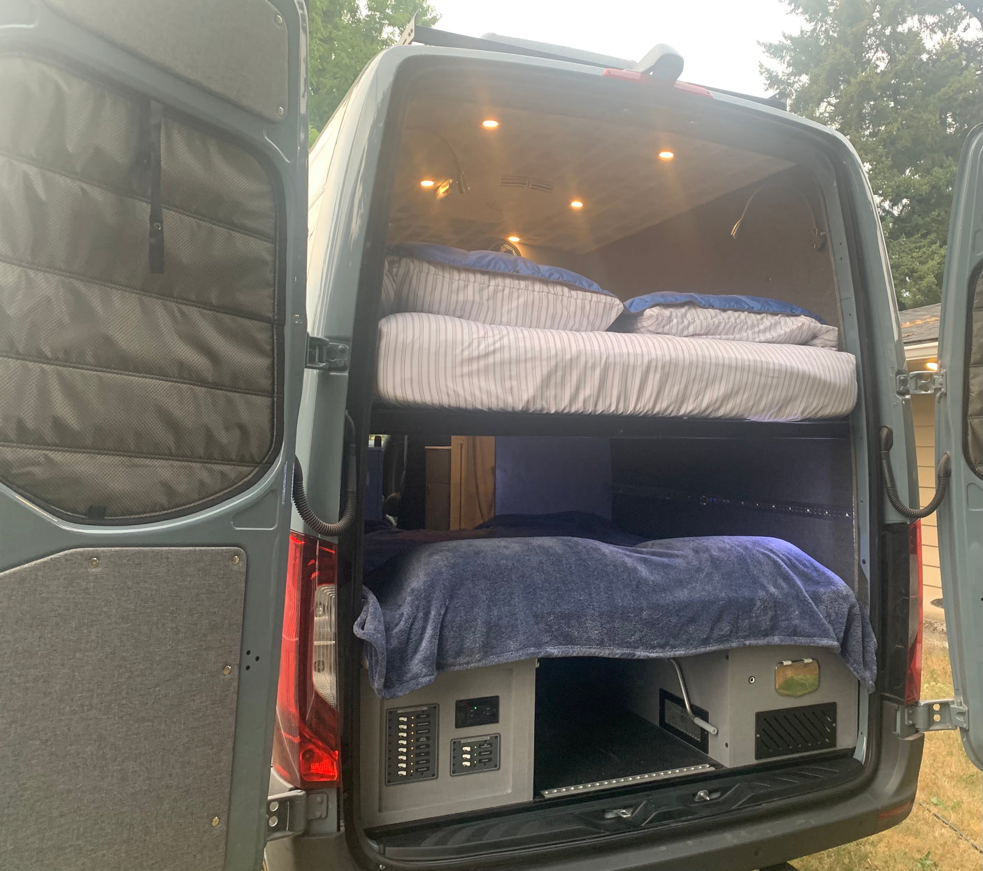 RV rental: Inside a custom camper van featuring built-in bunk beds & smart electrical/storage setup.