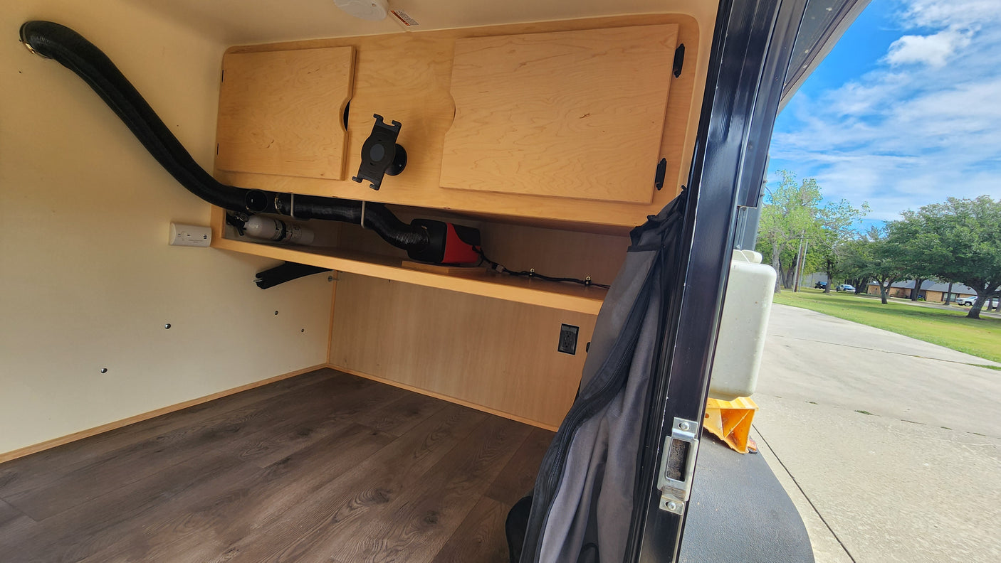 Compact RV rental interior with cozy wood details, featuring a heating system & power outlet for comfort.