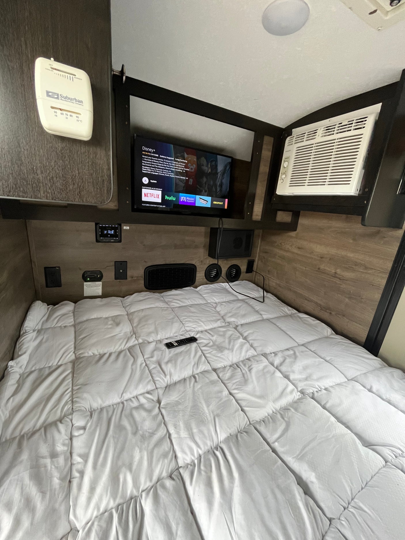 This RV rental offers a compact bedroom with a comfy bed, TV, AC, and climate controls for a cozy stay.