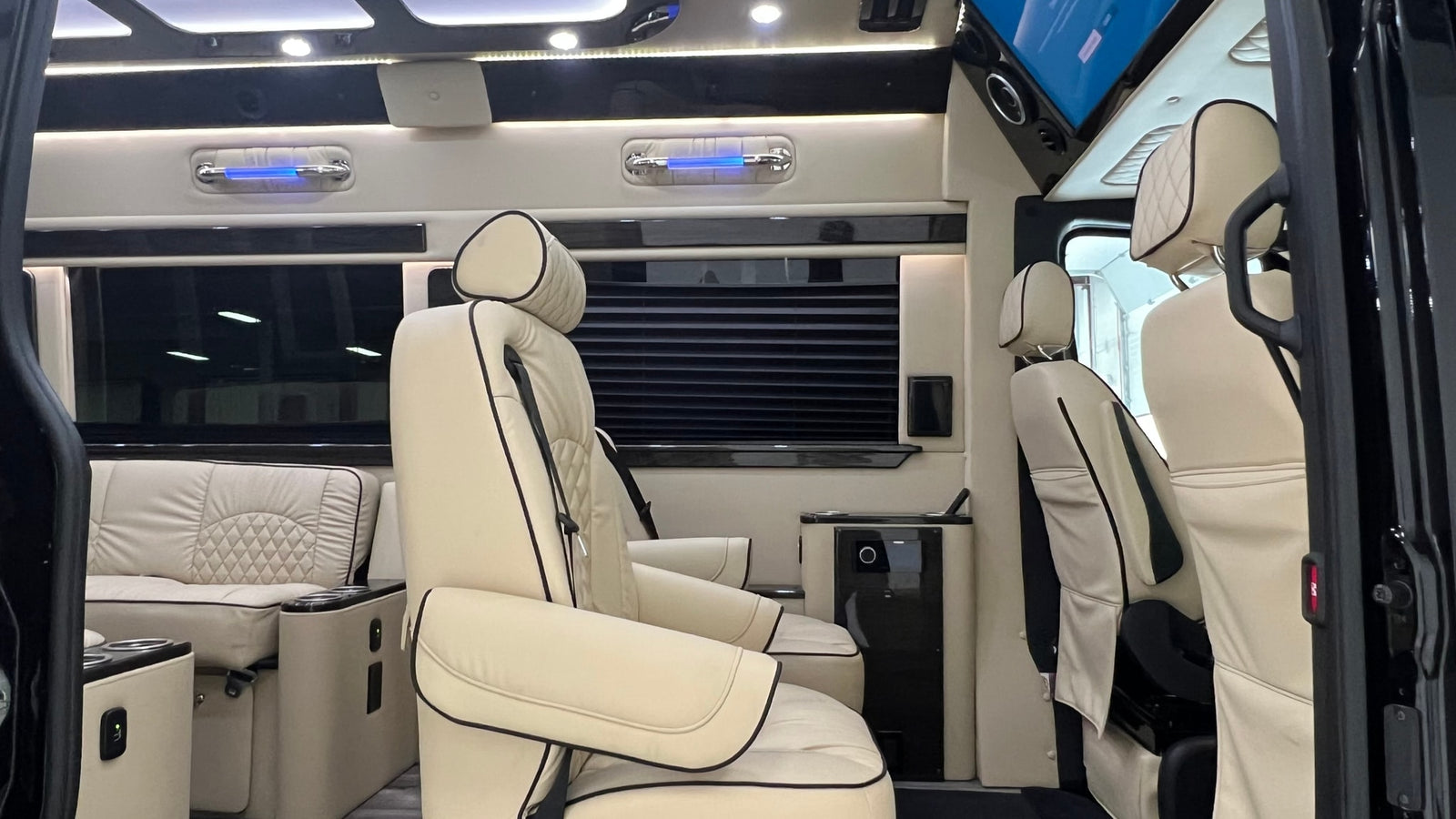 Luxurious cream leather interior of an RV rental, featuring custom captain's chairs and soft ambient lighting.