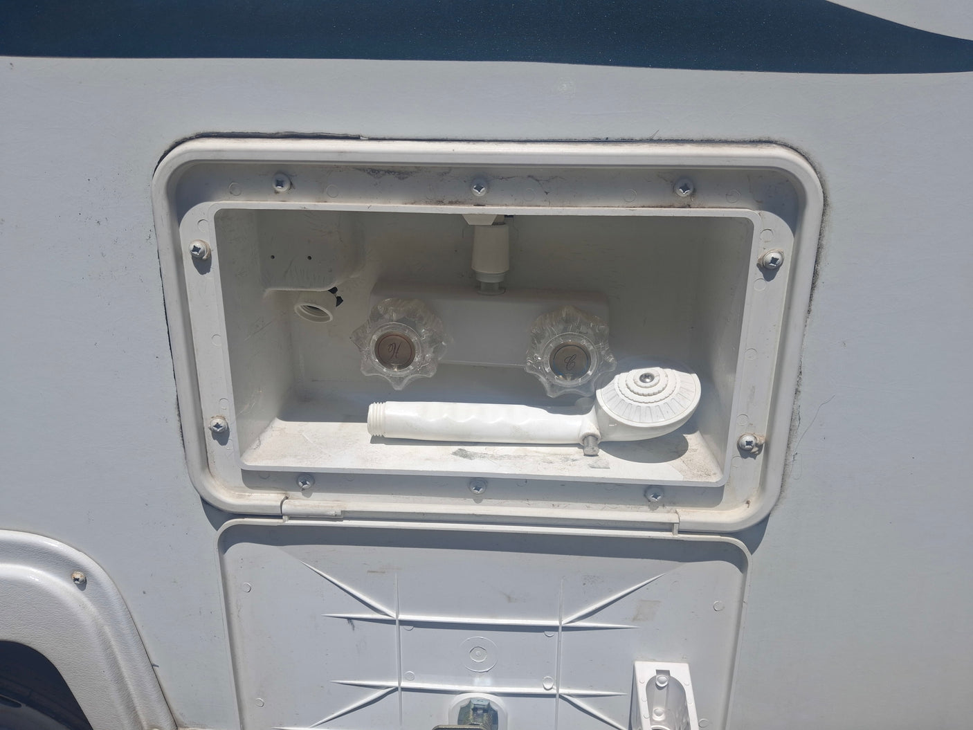 RV rental outdoor shower station with hot and cold water taps and hose, perfect for rinsing off on your camper.