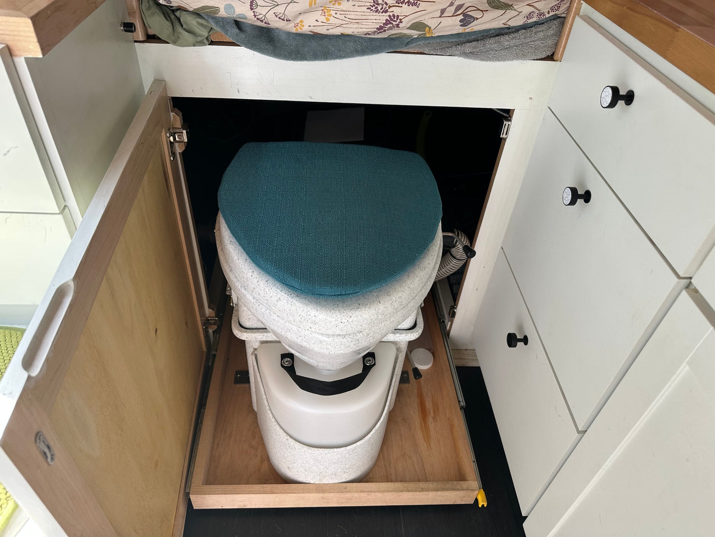 An RV rental features a composting toilet on a slide-out tray, cleverly integrated for discreet, accessible use.