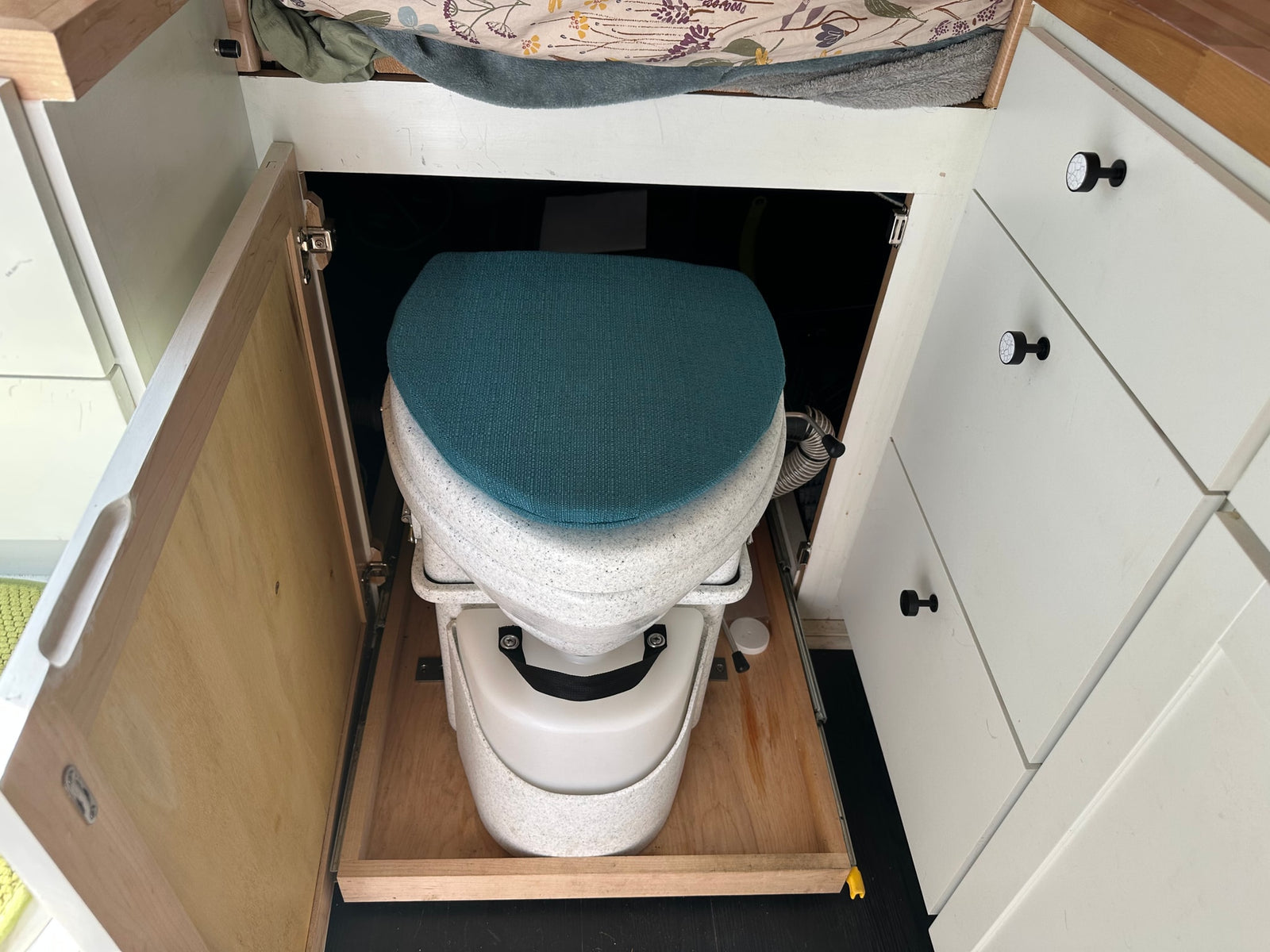 An RV rental features a composting toilet on a slide-out tray, cleverly integrated for discreet, accessible use.