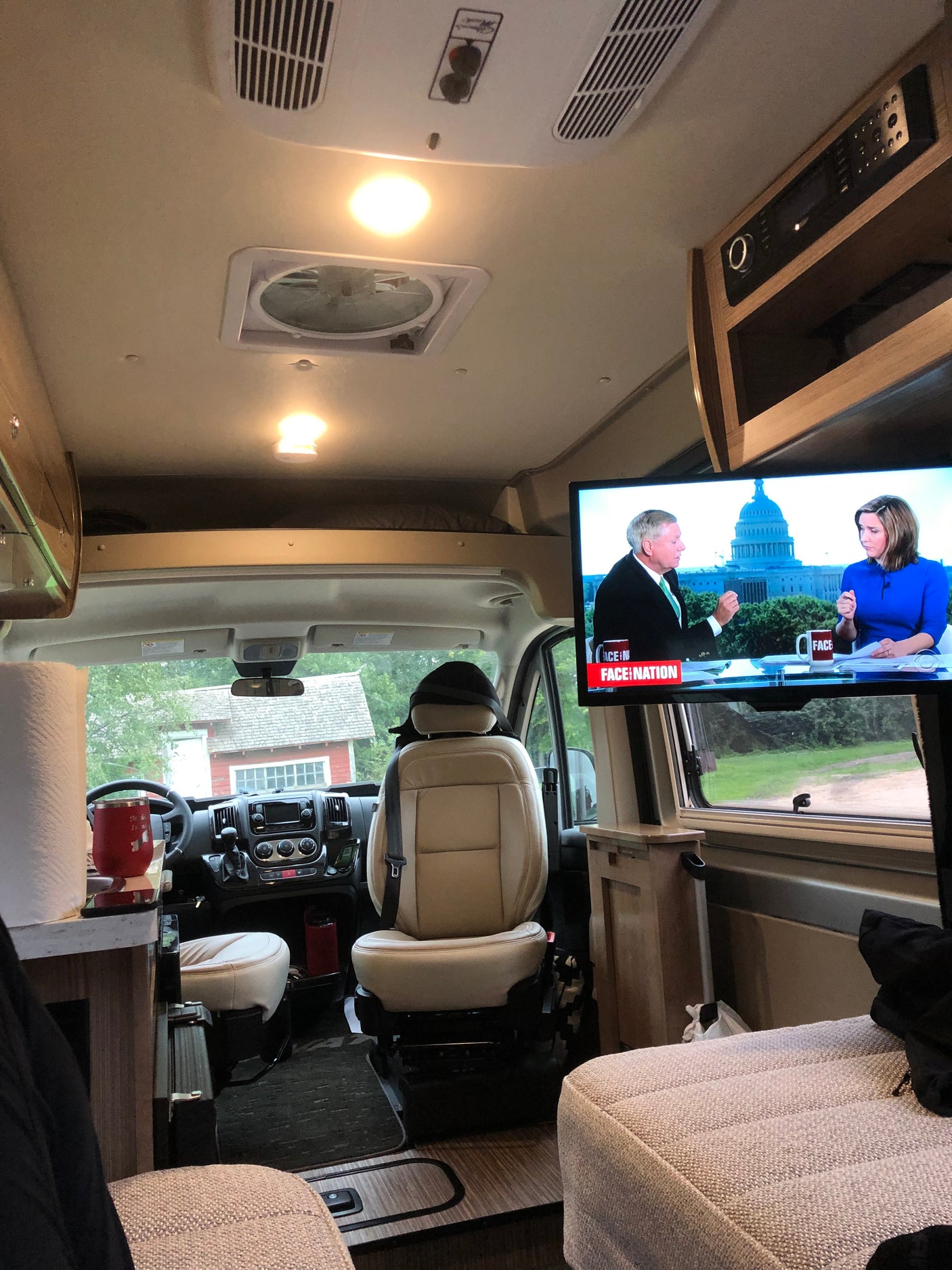 An RV rental's inviting interior. Watch news on TV from comfy seating, with the driver's area visible beyond.