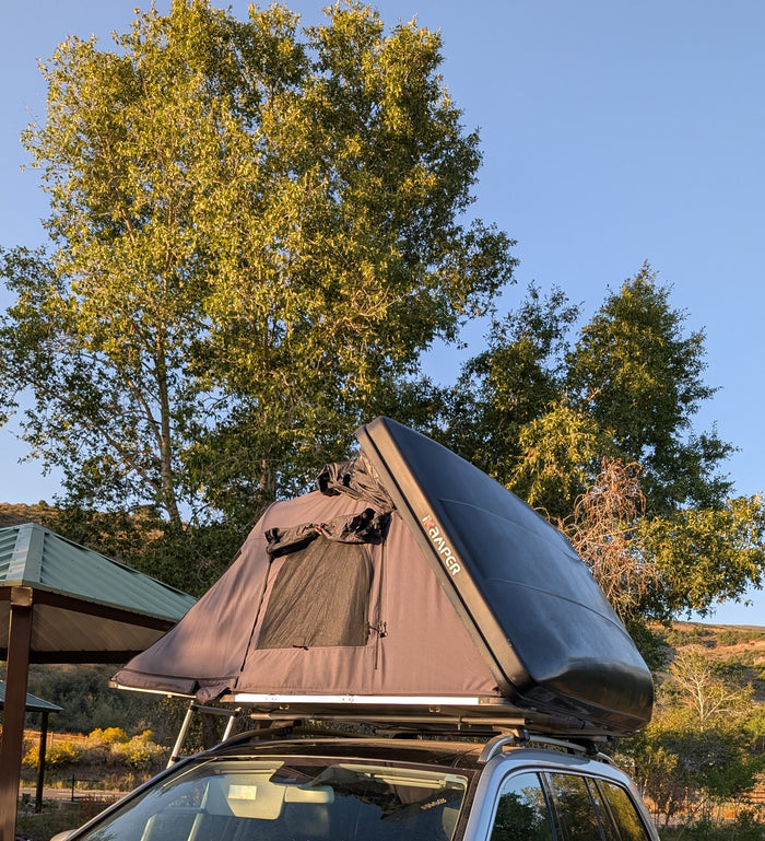 An iKamper rooftop tent unfolds on a vehicle, ideal for an RV rental outdoor adventure beneath sunny skies.
