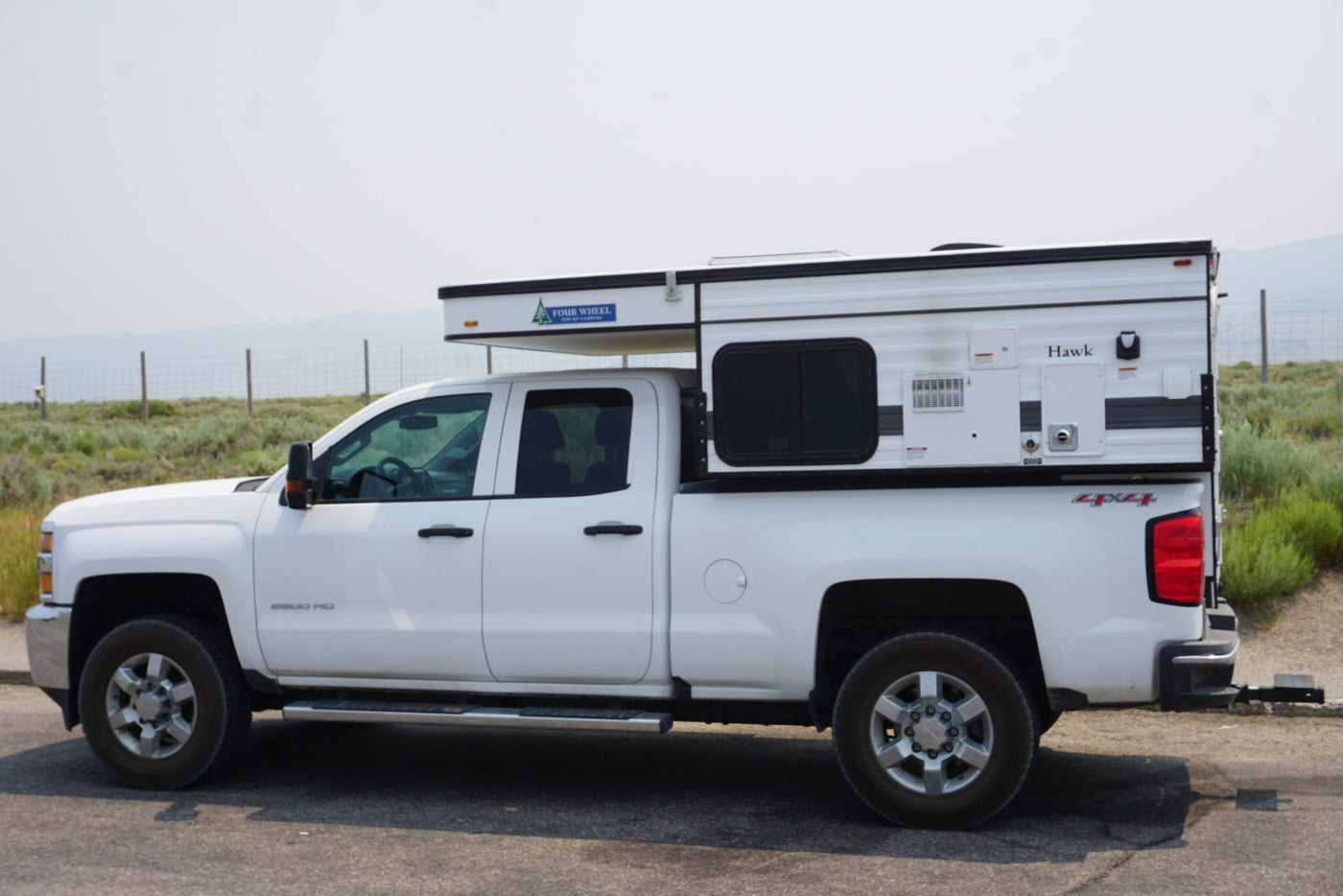 White Chevy 2500HD pickup with Four Wheel Hawk pop-up truck camper. Explore the outdoors with this RV rental! — photo 5