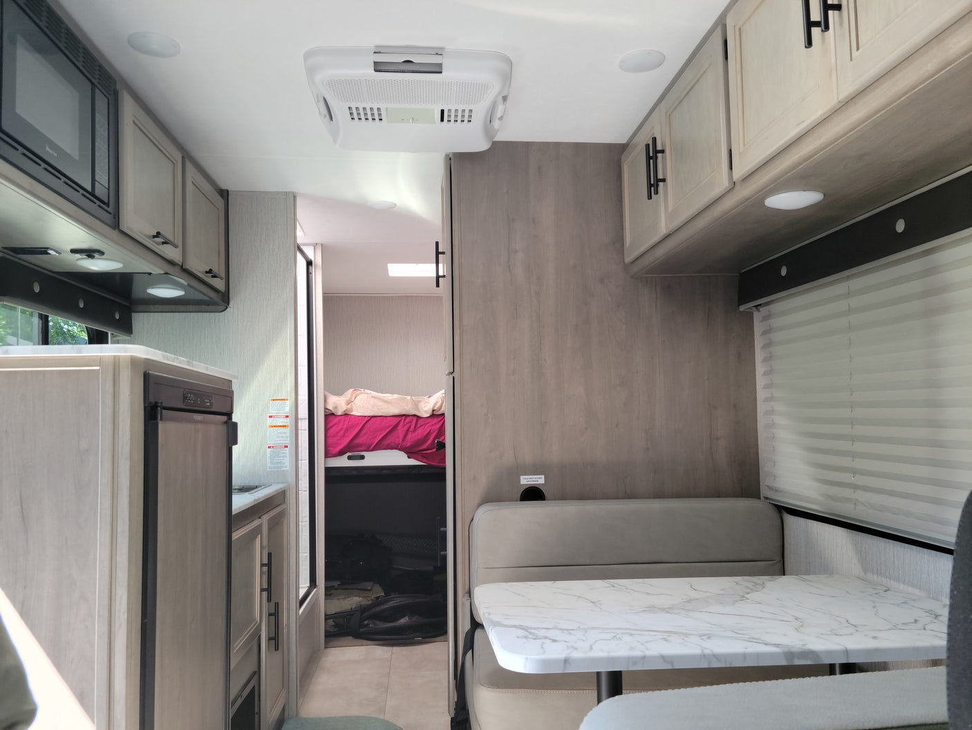 Bright, modern RV rental interior featuring a full kitchen, dining area, and rear bedroom. Perfect for family adventures.