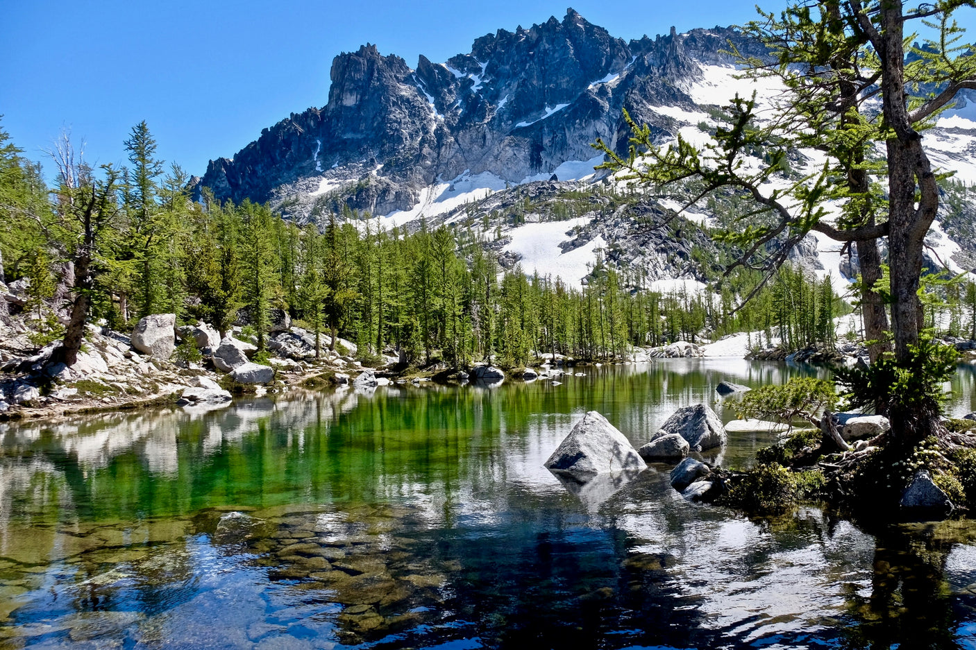 Experience breathtaking mountain landscapes! This vibrant alpine lake, surrounded by trees & snow-capped peaks, awaits your RV rental journey.