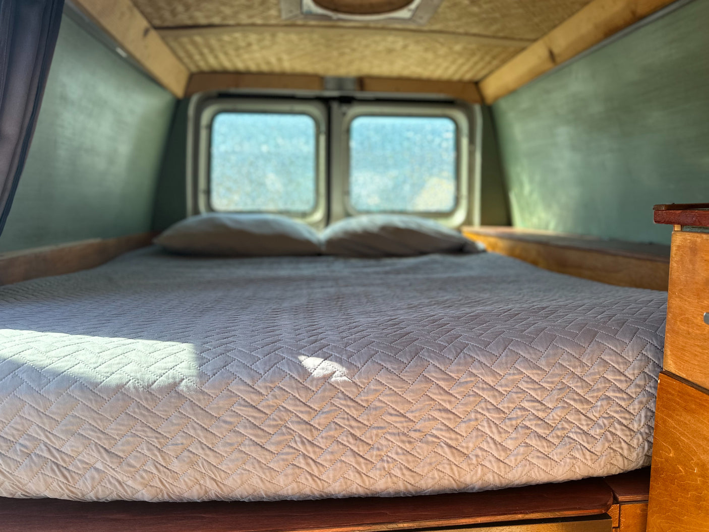 Relax in this cozy RV rental bed with natural light from the rear windows. Ideal camper interior for your travels.