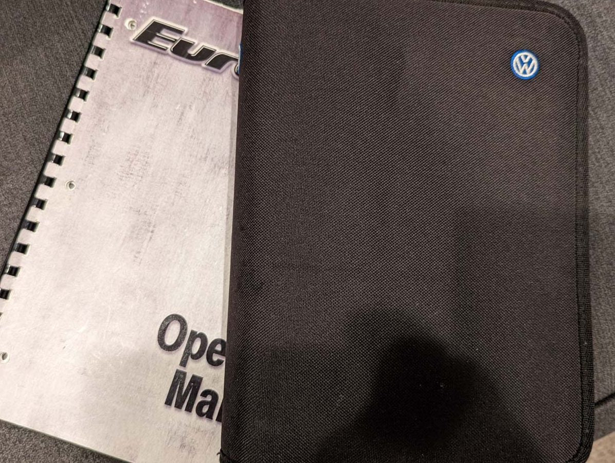 A black VW case and spiral-bound operating manual for an RV rental. Key vehicle info for the journey.
