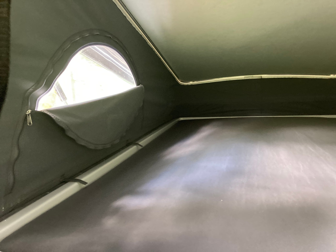 and pop-top access.|Scenic rv rental comfort: A bed with a geometric pillow overlooks a tranquil lake and forest through a mesh screen.|Interior of an RV rental: dark fabric walls — photo 5